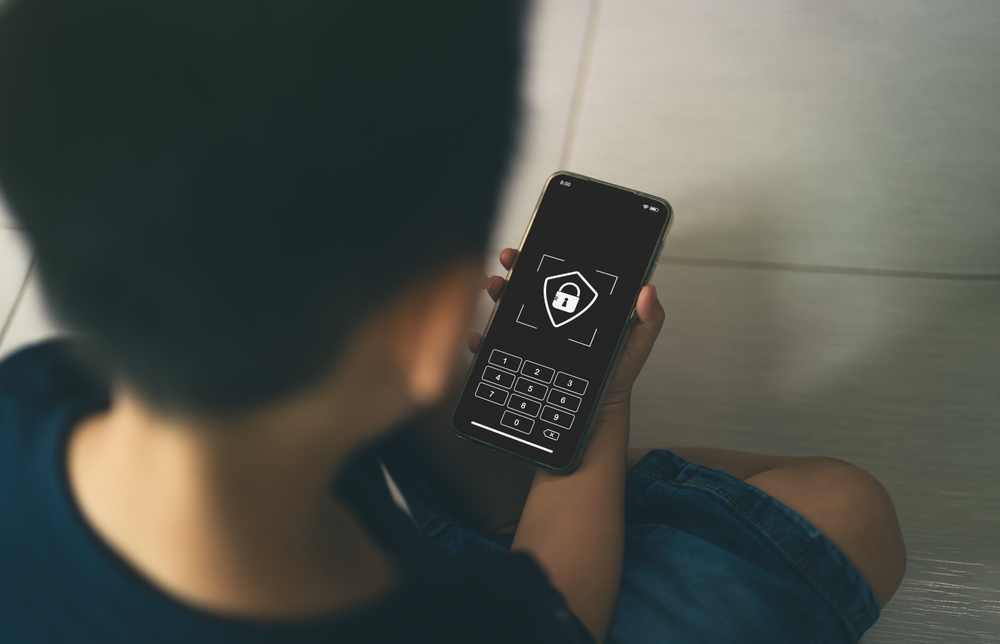 back,view,of,child,holding,smartphone,with,focus,on,screen
